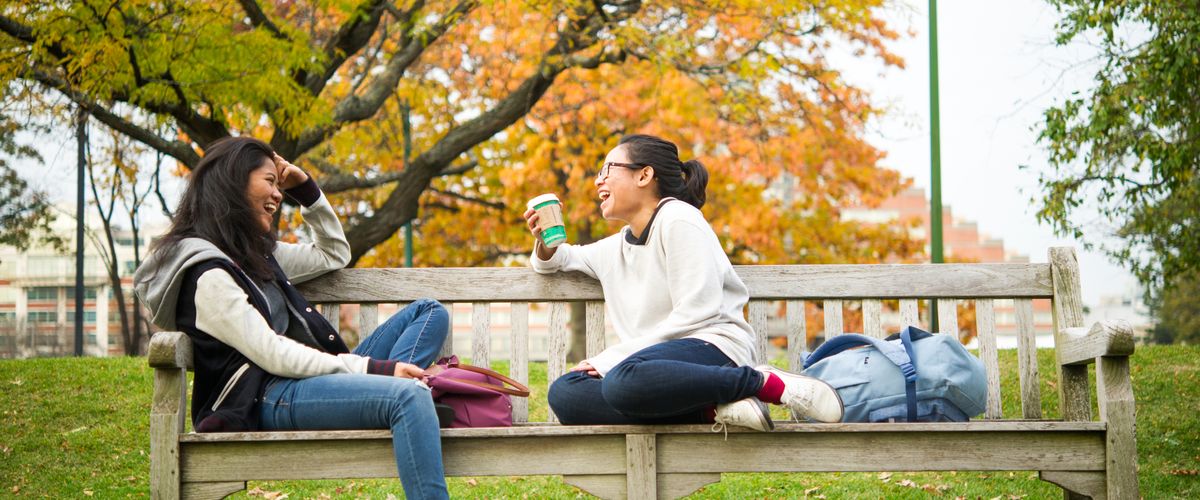 BU classmates chat on a bench