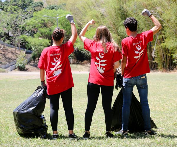 three Global Days of Service volunteers showing their muscles from behind